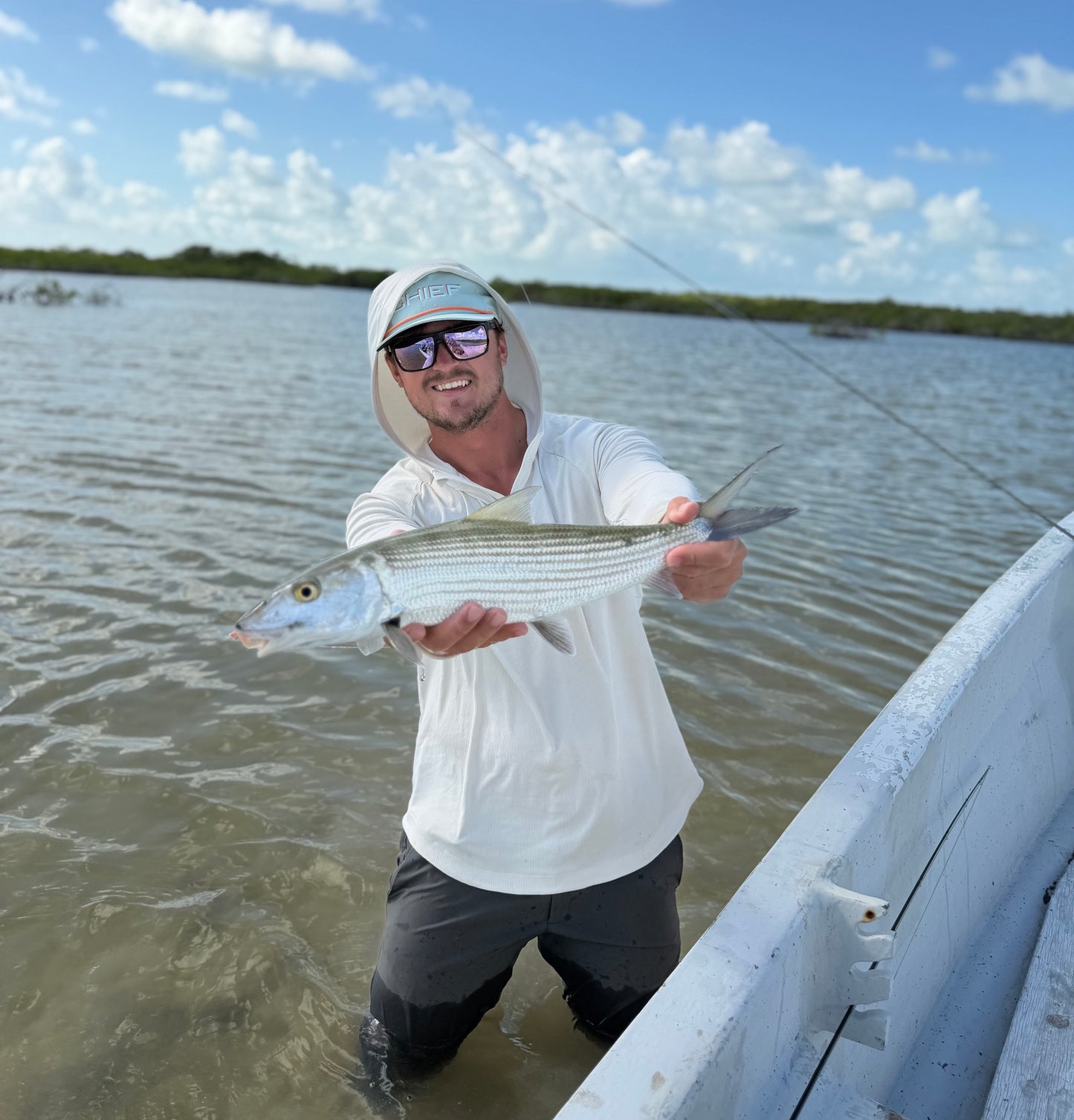 CHIEF Founder holding a Bonefish wearing OutCast Sun Hoodie Salt, CHIEF Glitch Logo Hat, and QuickDraw Pants