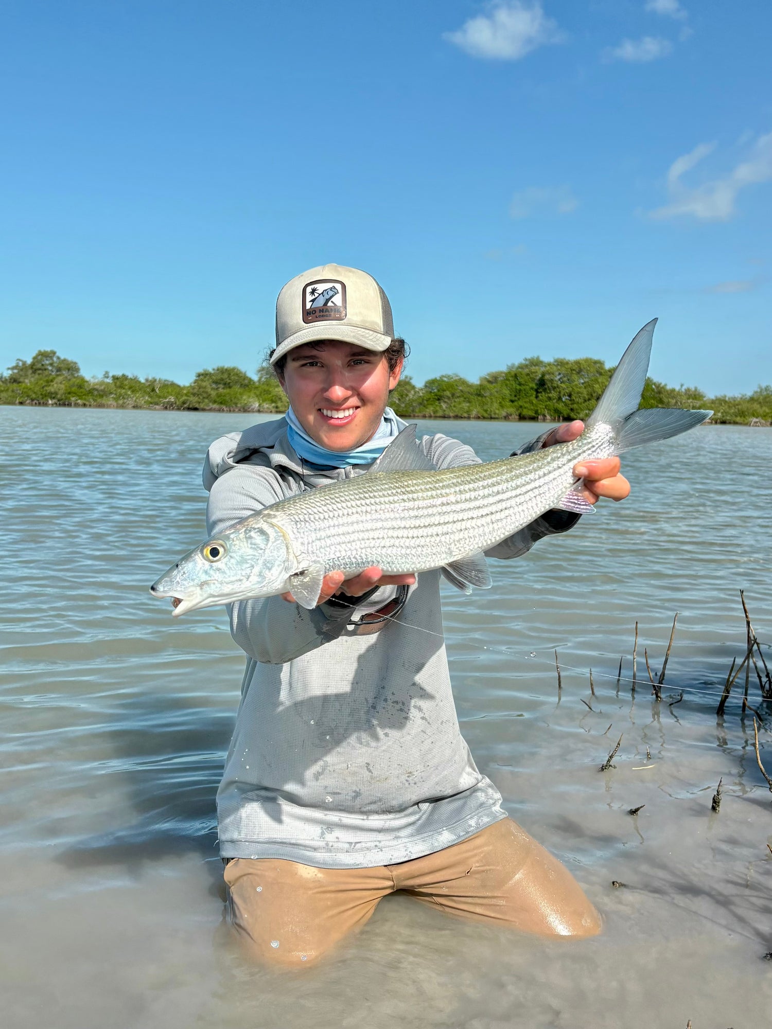Capt Andrew Spangler in OutCast Sun Hoodie Steel and QuickDraw Pants dust holding a Big Bonefish
